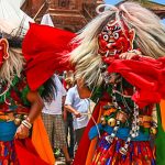 Two Lakhey dancers in traditional red masks with long white hair performing during the Gai Jatra festival in Nepal.