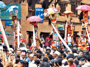 A large crowd of people celebrating Gai Jatra festival at Bhaktapur Durbar Square with historic temples in the background.