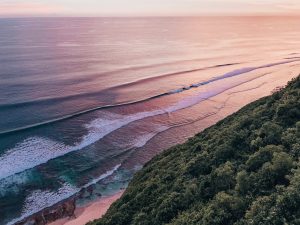 Sunset at Kuta Beach with gentle waves rippling toward the shore and a picturesque purple sky