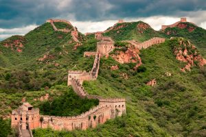 The Mutianyu section of the Great Wall of China winding through lush green mountains under a cloudy sky.