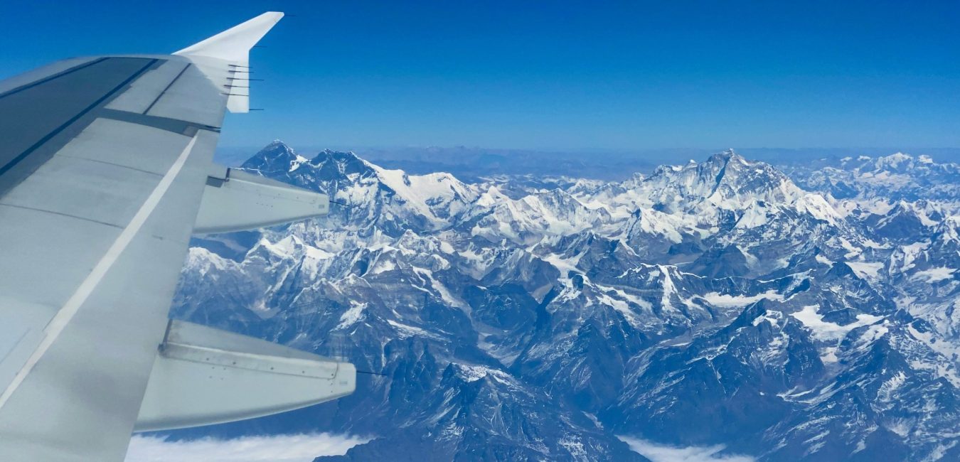 Aerial view of the snow-capped Himalayan mountain range and Mount Everest peaks seen from an airplane window.