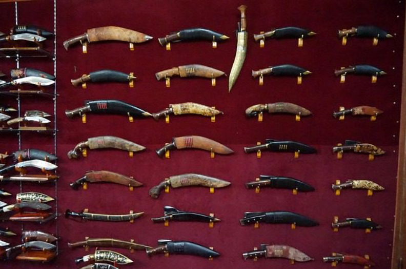 Extensive collection of traditional Nepalese Khukri knives on a red velvet display wall.