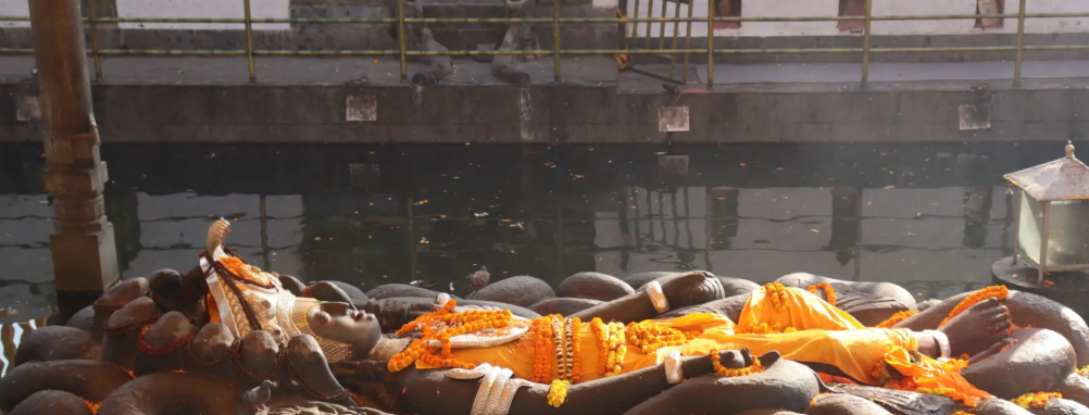 Reclining stone statue of Lord Vishnu floating in the sacred water pond at Budhanilkantha Temple, Kathmandu, Nepal.
