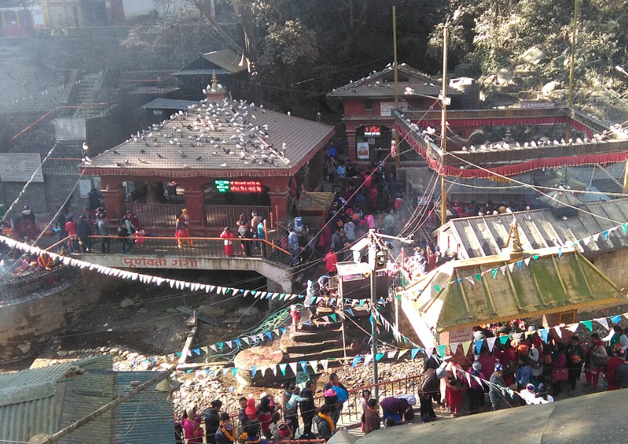 Aerial view of the crowded Dakshinkali Temple complex in Nepal with pilgrims and pigeons on the roofs.