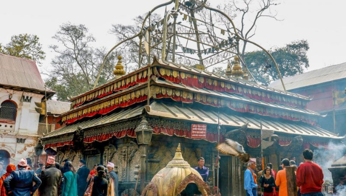 An outdoor, wide shot captures the traditional tiered multi-roof structure of the historic Guhyeshwari Temple in Kathmandu, Nepal.