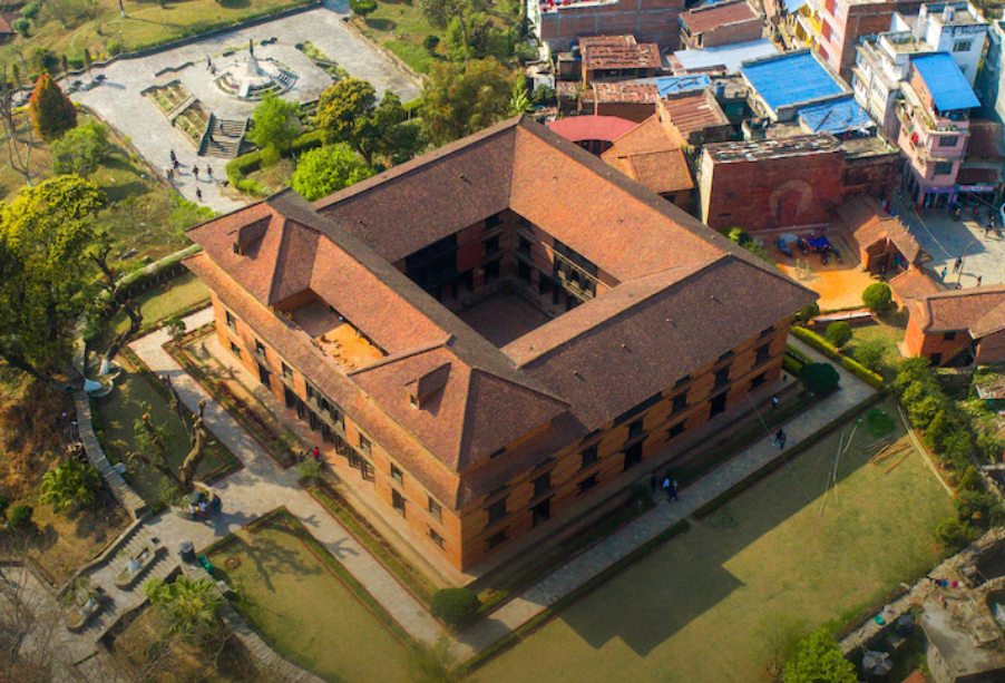 High angle aerial view of a traditional Newar red brick palace quadrangle and courtyard in Nepal surrounded by lush green lawns.