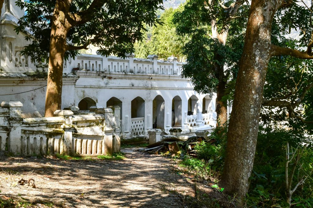 White neoclassical arches and tiered balconies of Ranighat Palace (Rani Mahal) framed by large trees in Palpa, Nepal.