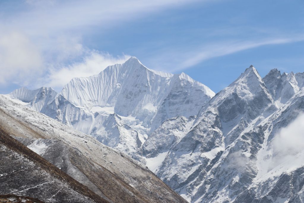 Snow-capped Gangchempo mountain peak with distinctive vertical fluted ridges under a blue sky in Langtang Valley, Nepal.