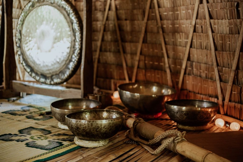 Hand-hammered Himalayan singing bowls and a traditional bronze gong in a rustic meditation studio in Nepal.