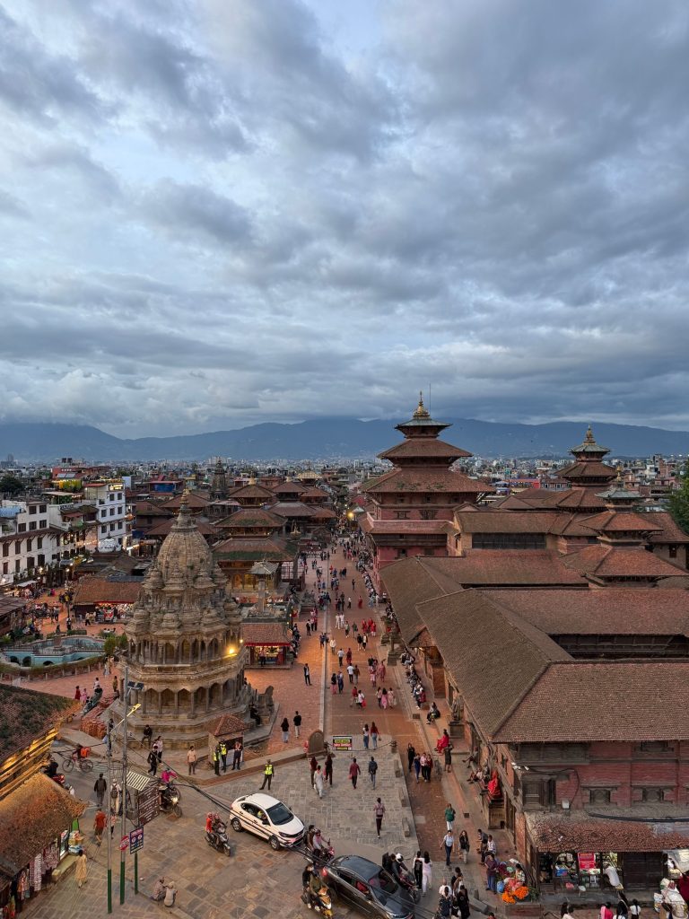 Aerial view of Patan Durbar Square in Lalitpur, Nepal, featuring the Krishna Mandir temple and traditional Newari architecture under a cloudy sky.