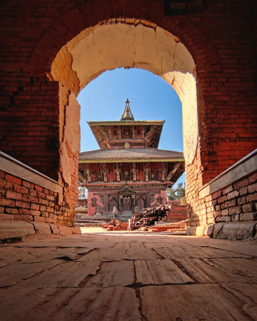 View through a brick archway of the historic two-story Changu Narayan pagoda temple in Bhaktapur, Nepal.