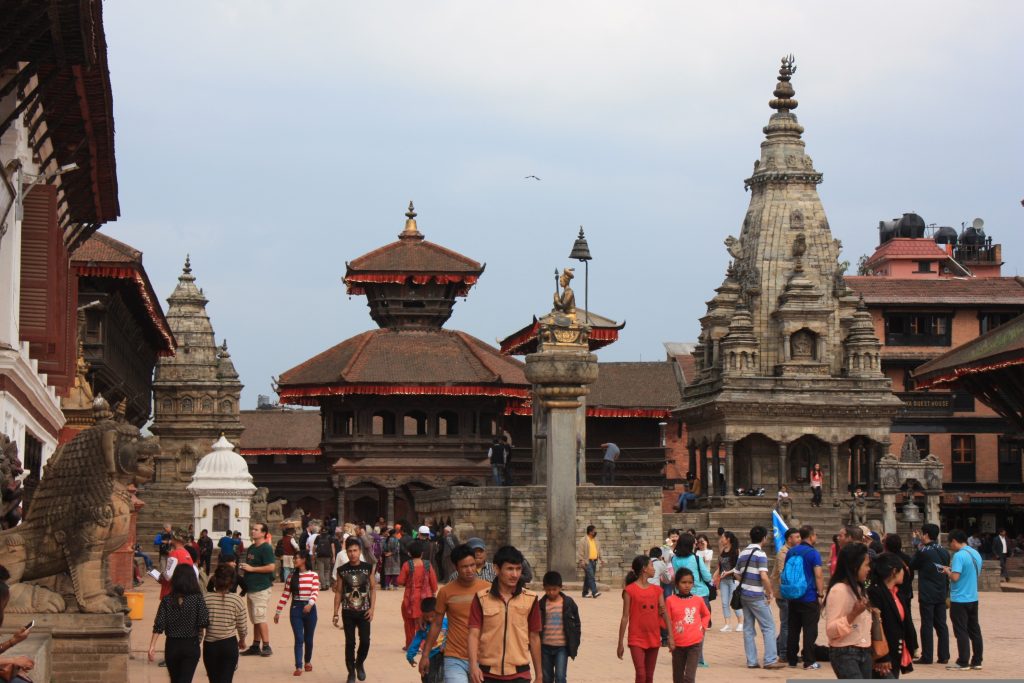 Intricately carved pagoda temples and stone monuments at Bhaktapur Durbar Square, a UNESCO World Heritage Site in Nepal, with traditional Newari architecture and local visitors.