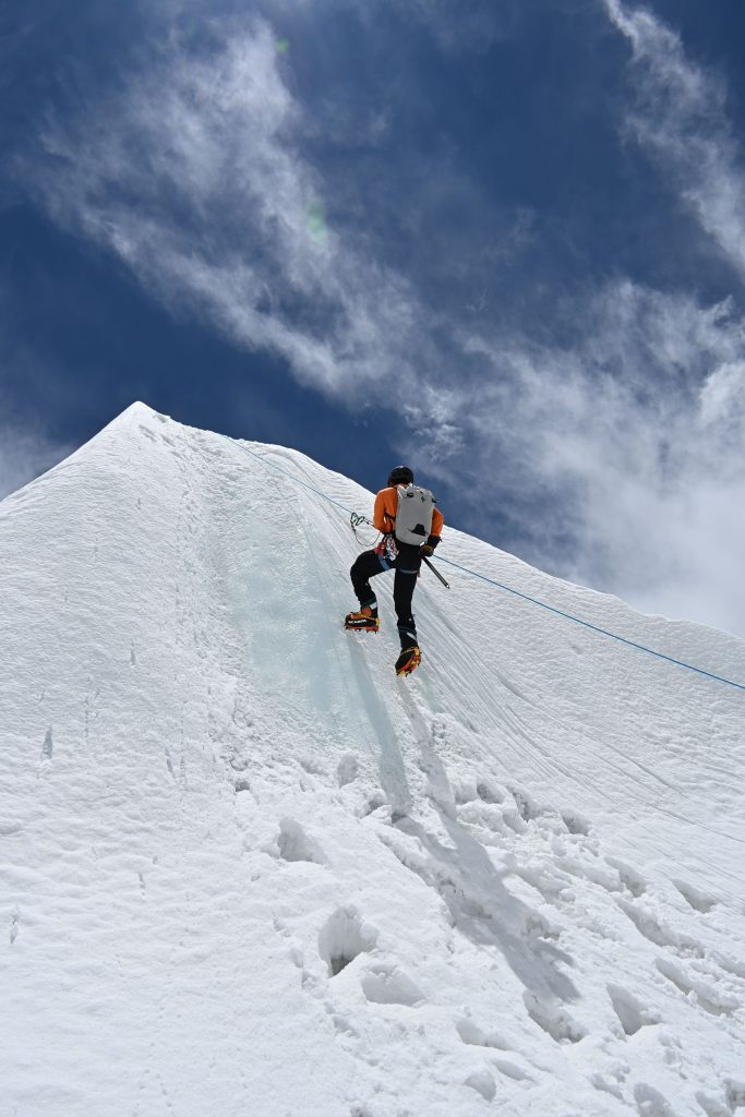 The Ultimate Guide to Adventure Activities in Nepal: Mountaineer using fixed ropes and crampons to ascend the steep snow headwall on Island Peak Imja Tse in Nepal.