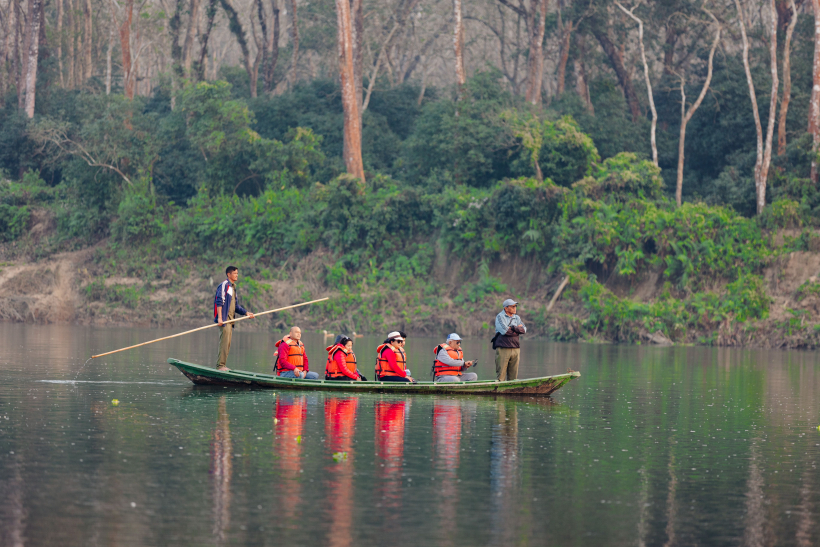 The Ultimate Guide To Adventure Tourism In Nepal: Tourists wearing orange life jackets on a traditional dugout canoe safari along the Rapti River in Chitwan, Nepal